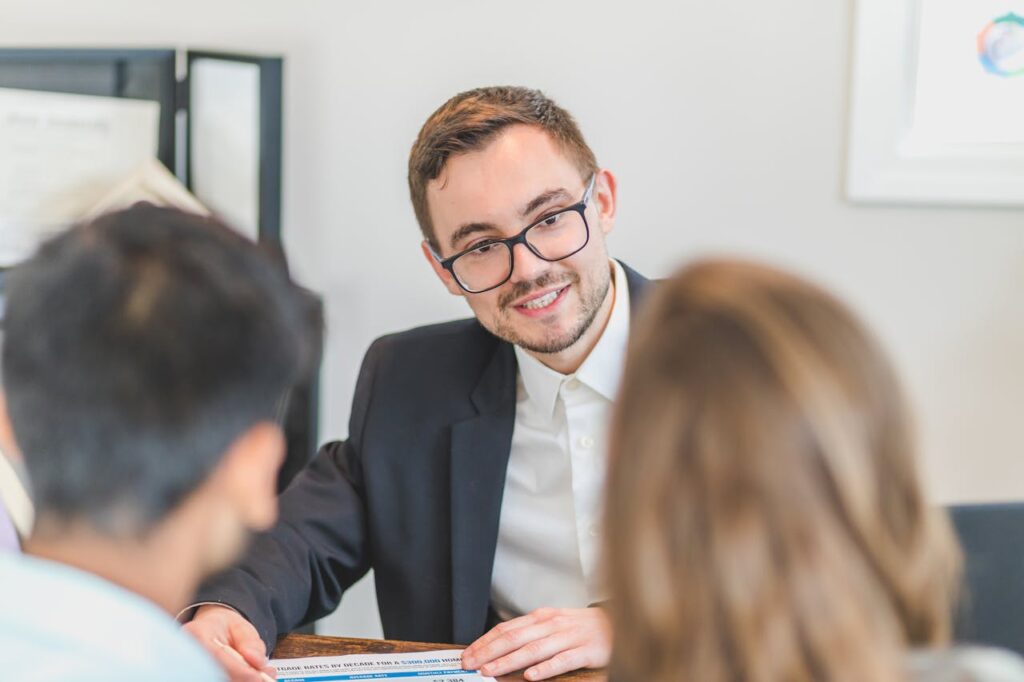 Smiling businessman in a suit and eyeglasses during a team discussion.